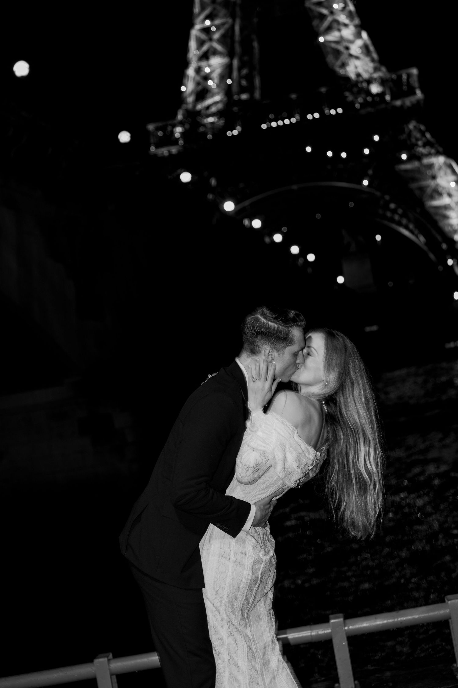 A romantic nighttime scene with string lights creating a magical ambiance as a couple shares an intimate moment outdoors. Paris editorial