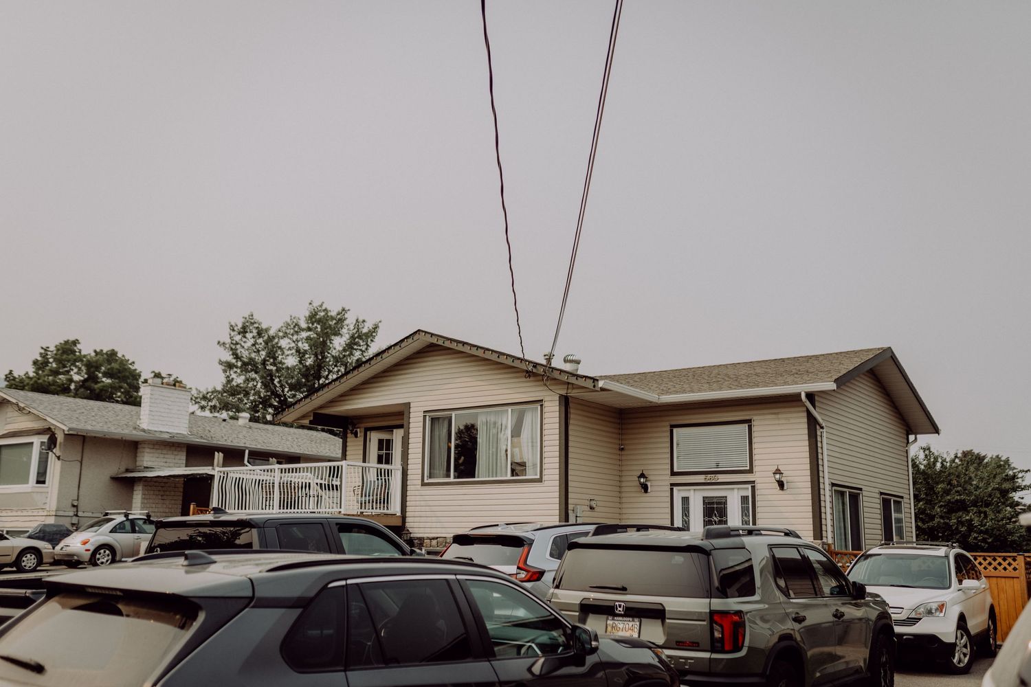 A series of single-story ranch houses with driveways and parked vehicles line a residential street.