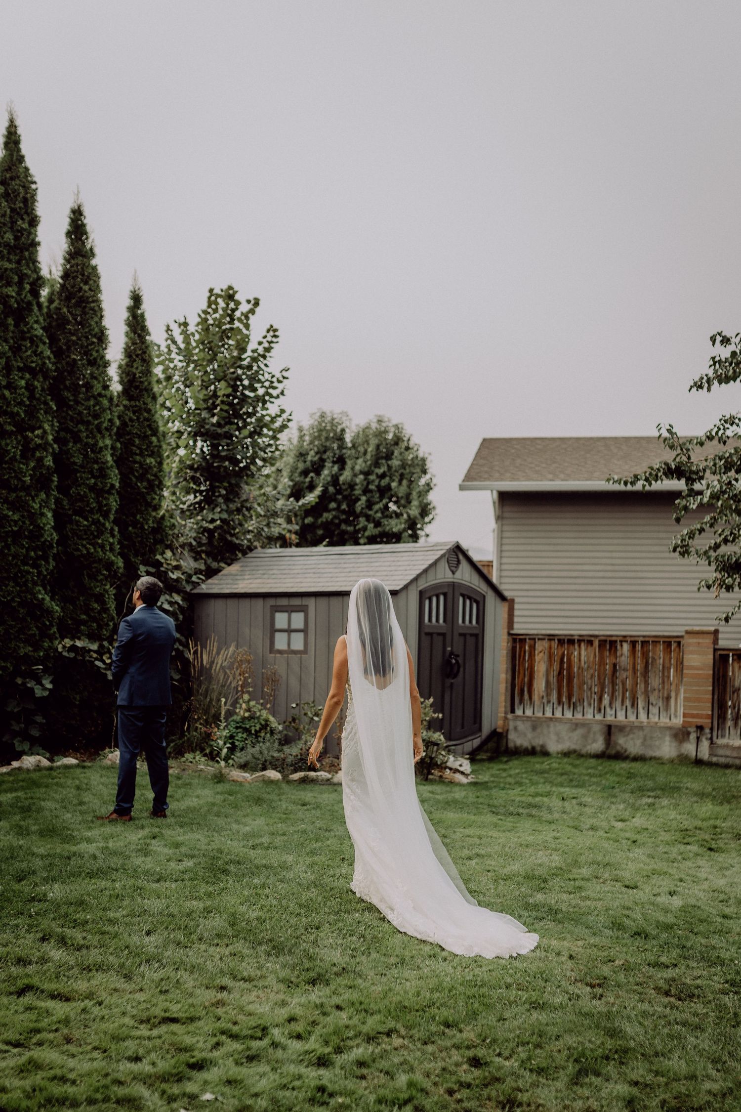 A series of wedding photos showing a couple walking across a green backyard lawn with wooden fences and houses in background.