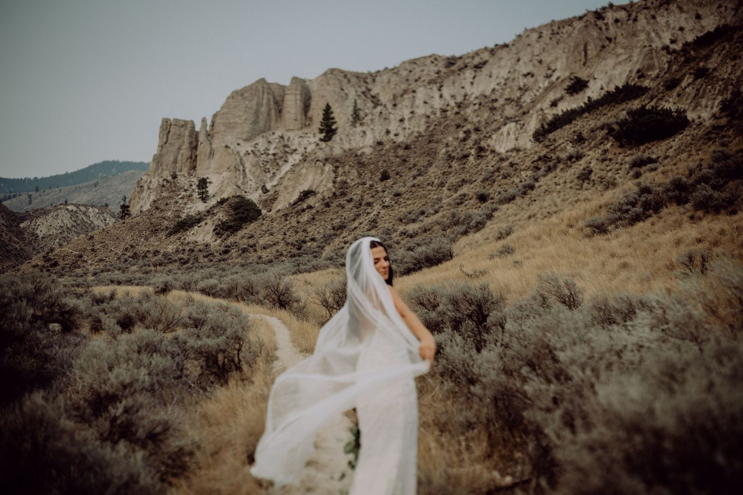 Newlywed couple embraces in front of dramatic desert rock formations at sunset.