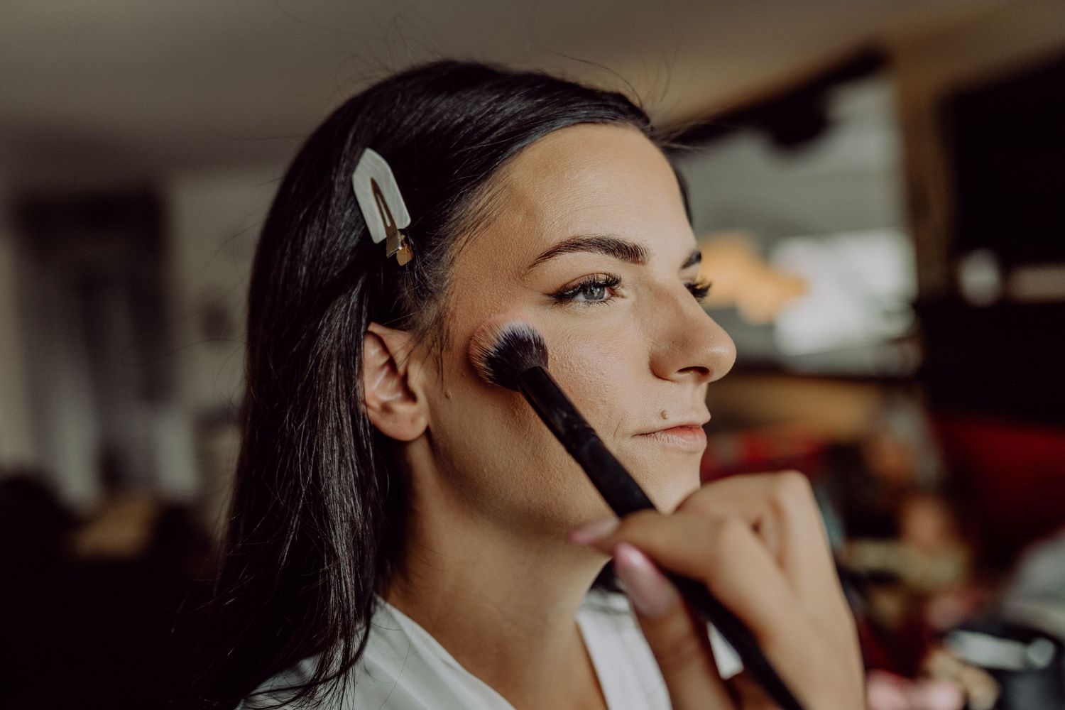 A sequence of images shows someone applying makeup with brushes in a professional setting.