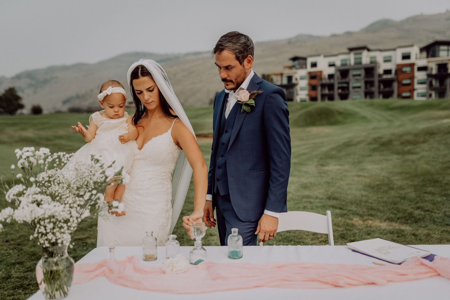 A couple celebrates their wedding day outdoors with baby's breath floral arrangements and scenic mountain views.