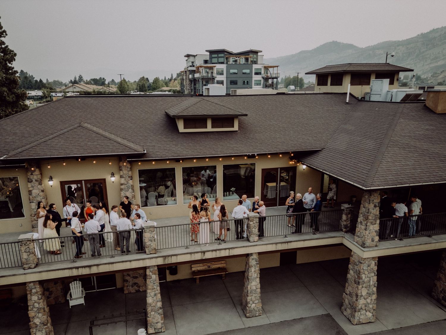 Guests gather on a rustic covered deck overlooking scenic mountain views during an outdoor event.