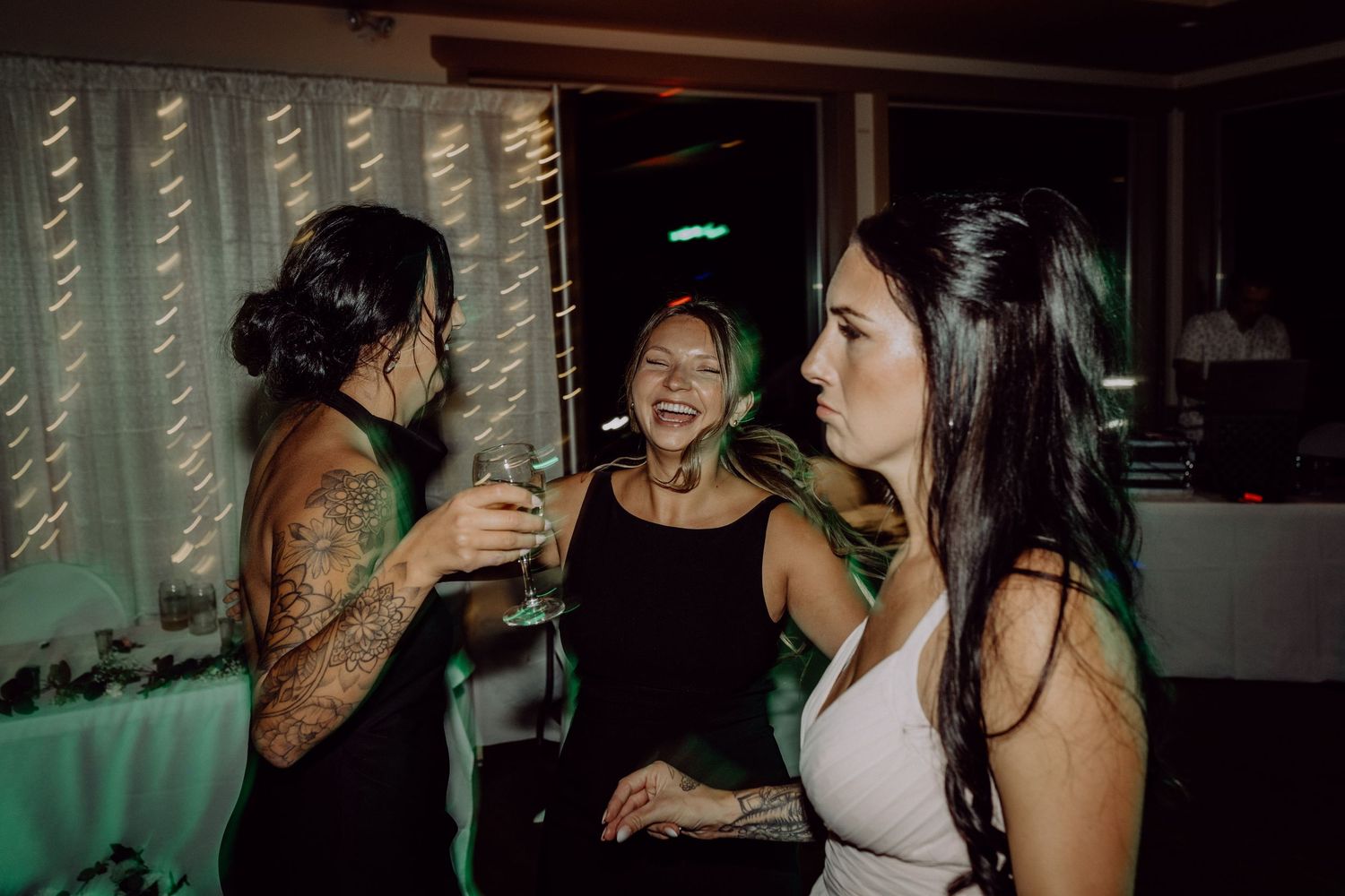 People dancing and socializing at a dimly lit party or nightclub with green lighting effects.