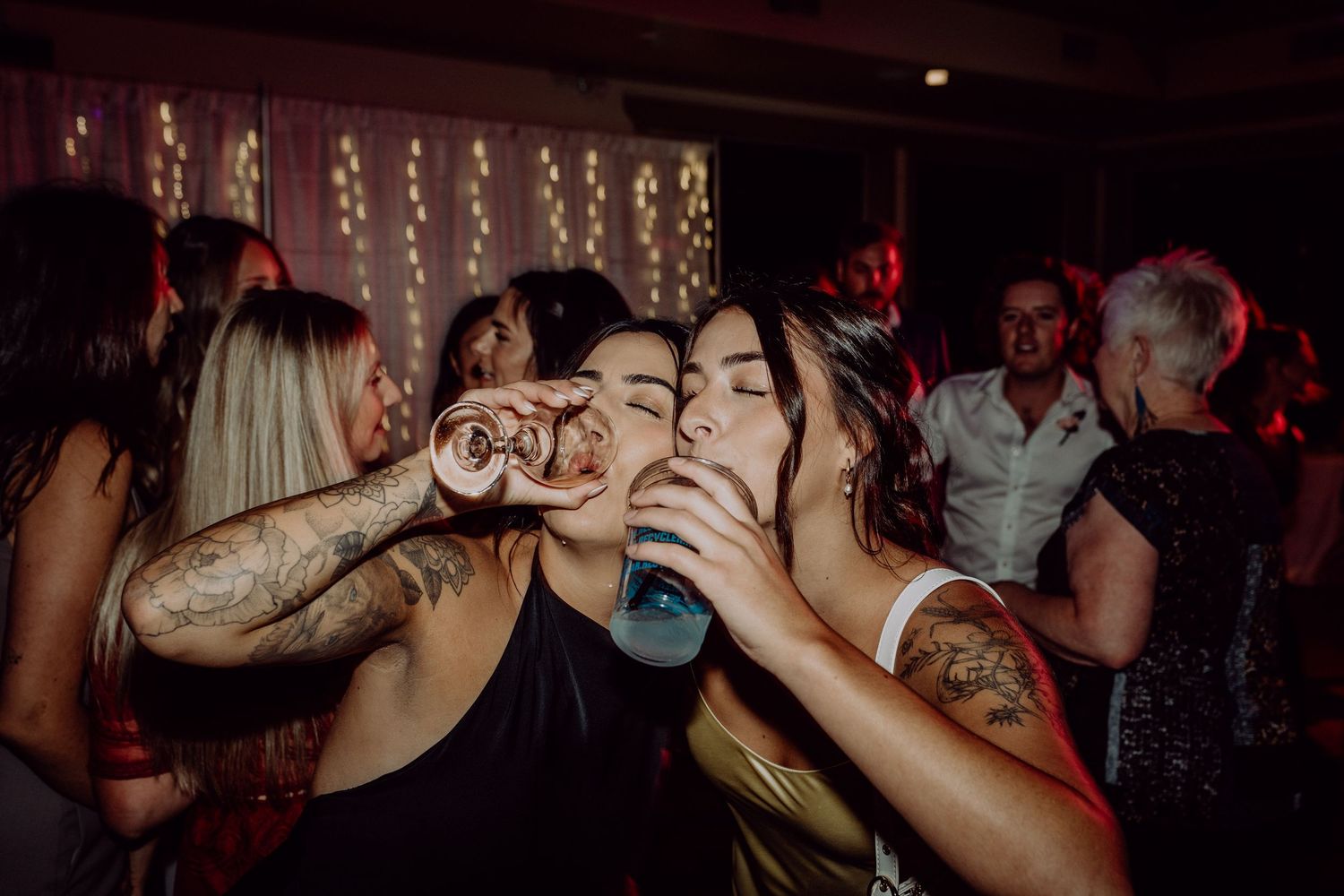 People dancing and socializing in a dimly lit nightclub with red lighting.