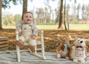 Outdoor photography setup with white chair and personalized decorations on blanket.