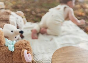 Decorative elements including beads and a blanket arranged for a first birthday photoshoot outdoors.