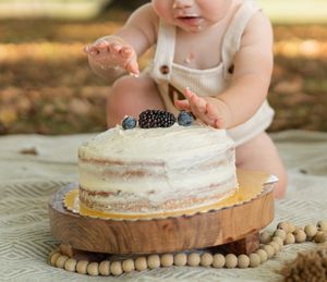 Close-up of a rustic naked cake on a wooden board during an outdoor celebration.