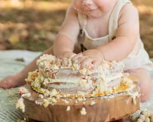 Close-up of cake smashed and crumbled on a wooden board during a birthday celebration.