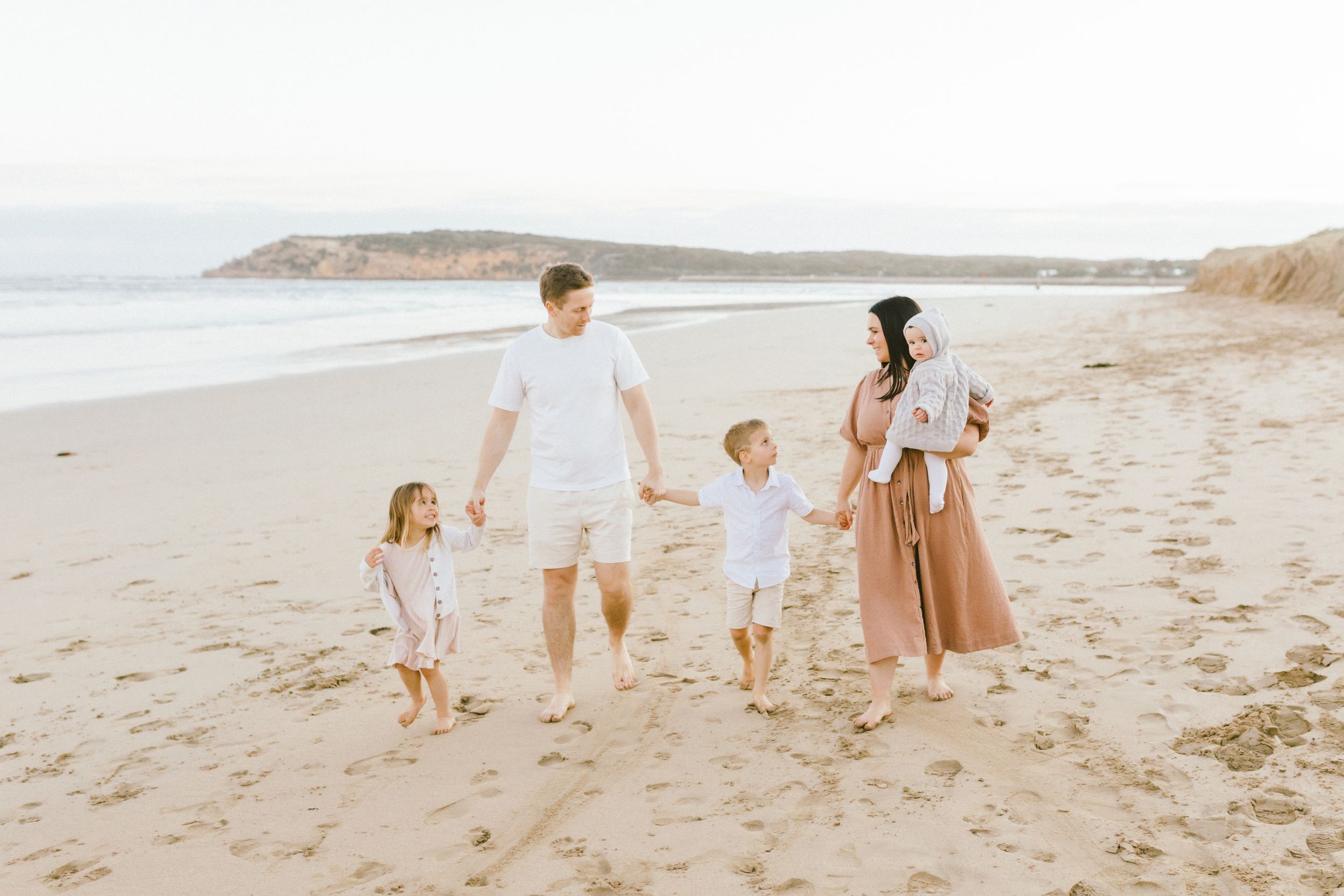 Family enjoying a peaceful walk together along a scenic beach during golden hour.