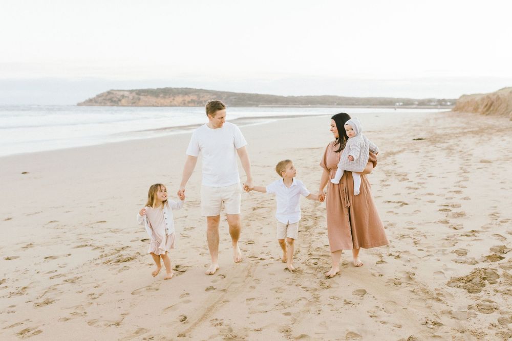 Family enjoying a peaceful walk together along a scenic beach during golden hour.