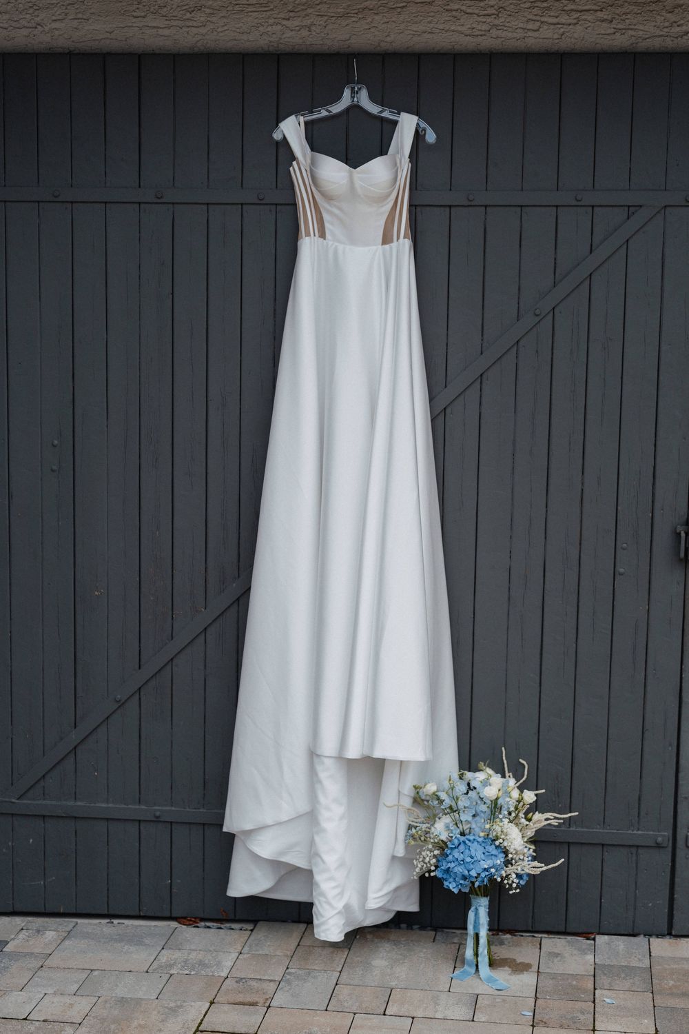Brautkleid ist an alter Hoftür elegant aufgehängt und präsentiert.