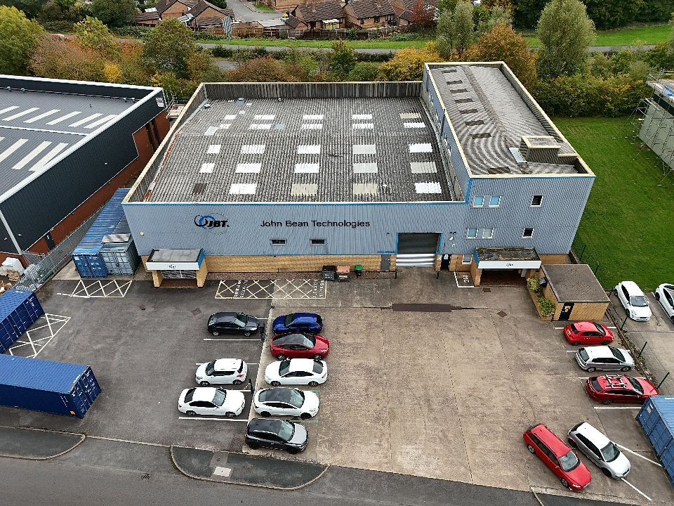 Aerial view of a parking lot outside a commercial building with several red and white vehicles parked in marked spaces.