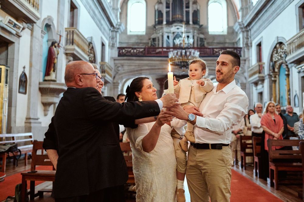 A family stands at the church altar as a priest blesses their baby during a baptism.