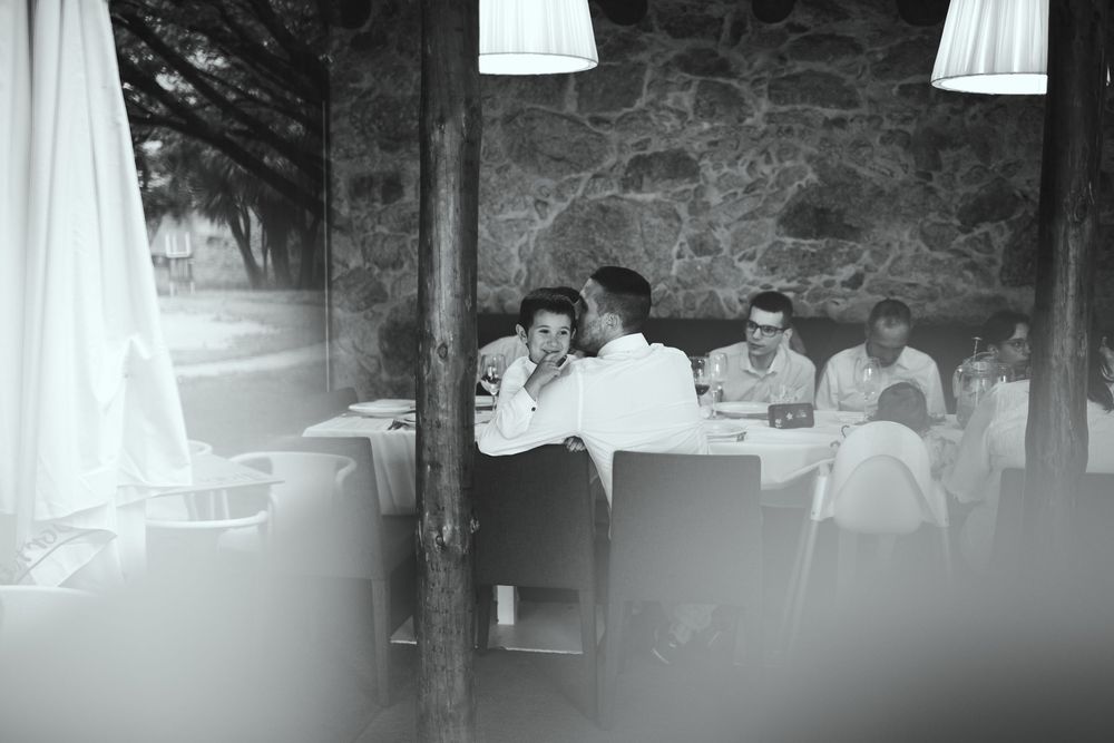 A couple shares an intimate moment at a restaurant table in a black and white photo.