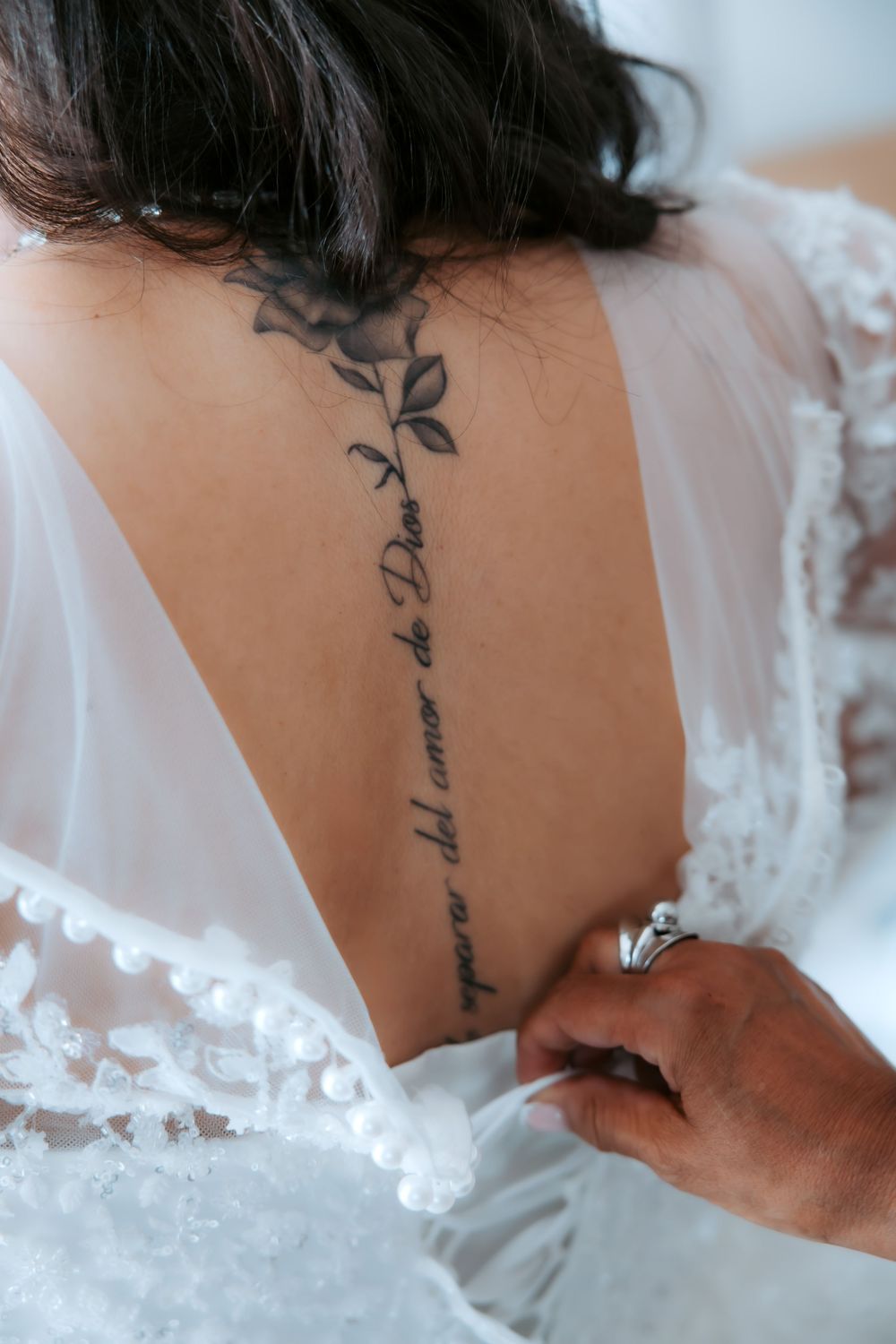 Close-up view of a delicate white lace wedding dress detail against a light background.