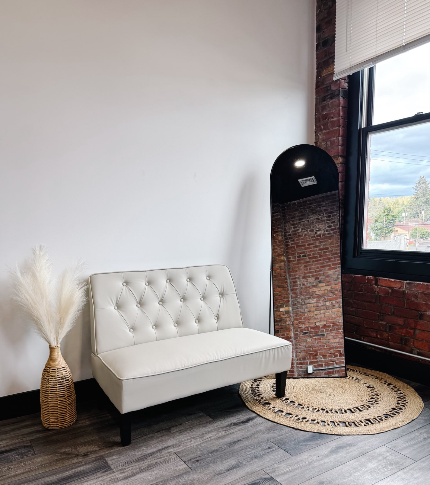 Modern white tufted sofa against exposed brick wall with natural light and decorative elements.