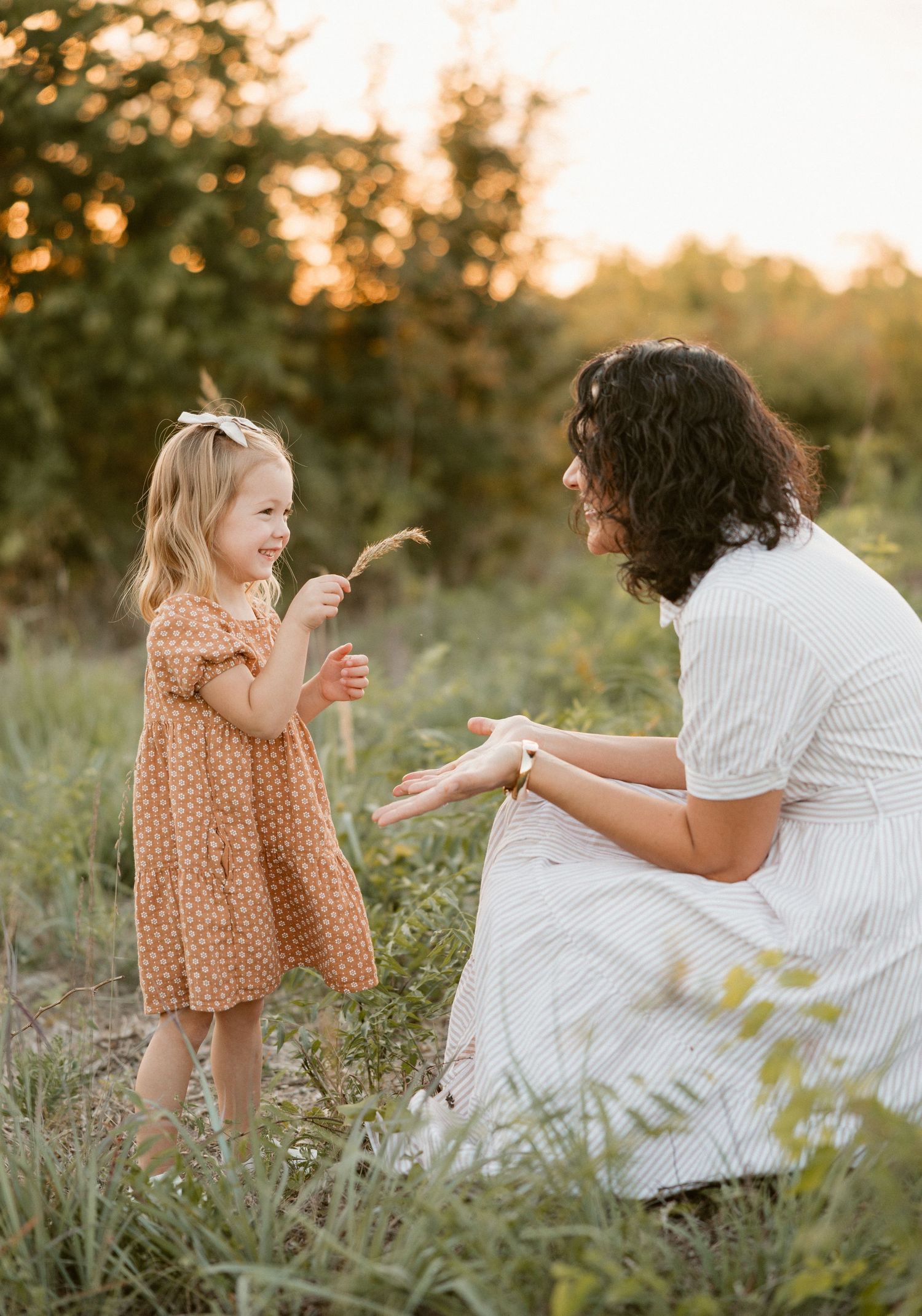 Two people share a playful moment together in a sunlit meadow at golden hour.
