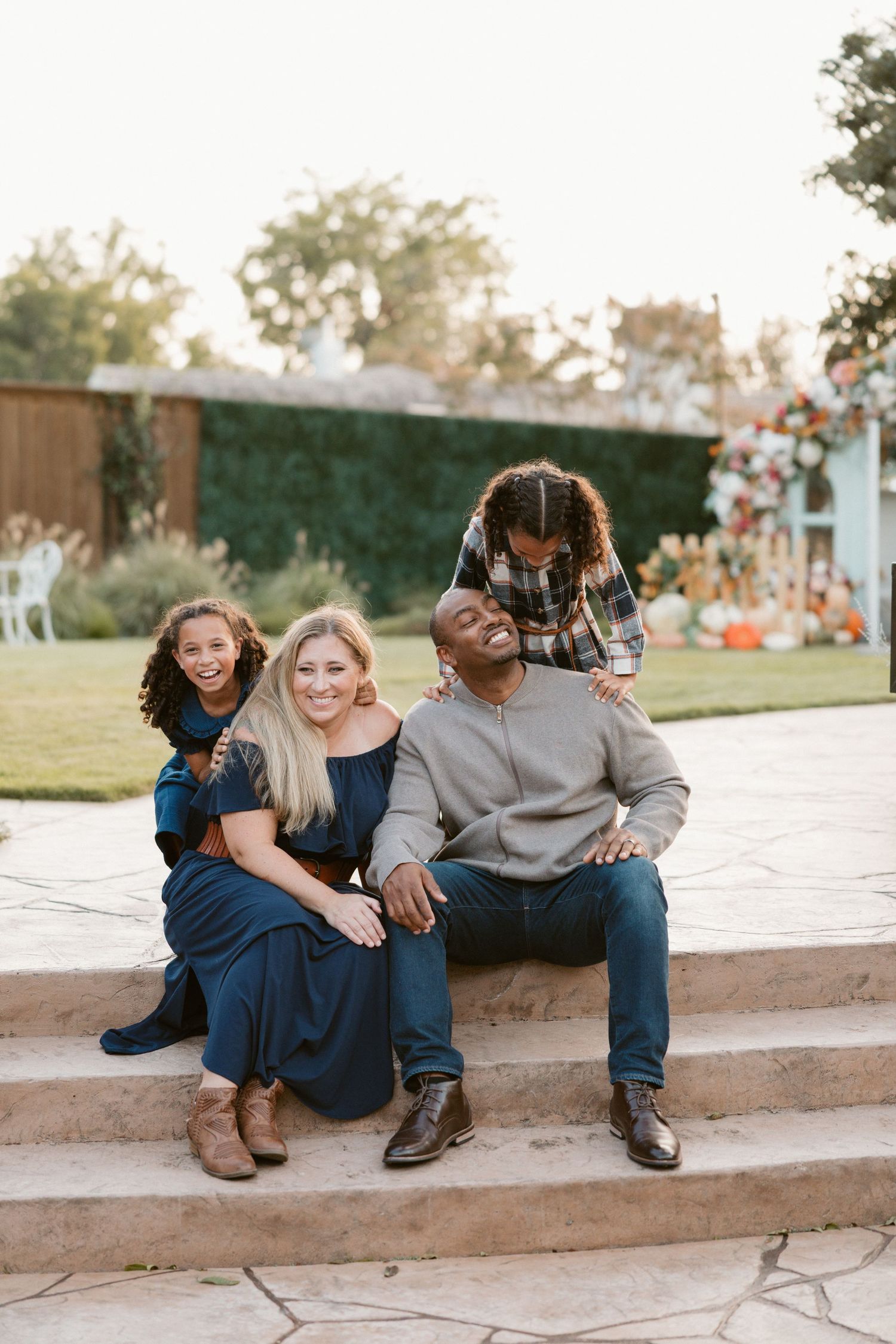 Three people sitting together on concrete steps sharing a candid moment at sunset.