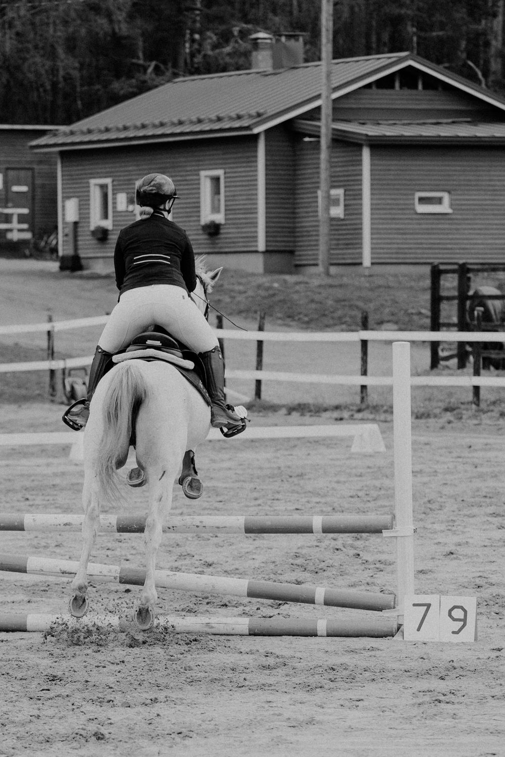 A sequence of four black and white photos showing a horse and rider jumping over an obstacle in an arena.