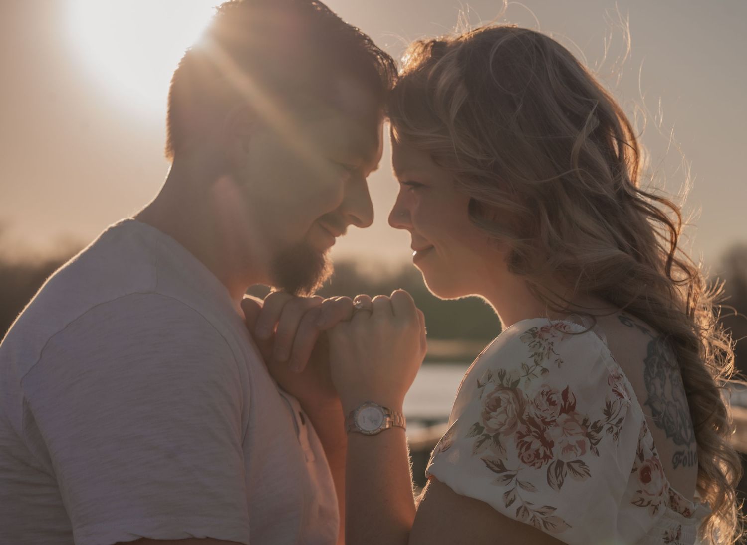 A romantic couple sharing tender moments during a sunset wedding photoshoot.