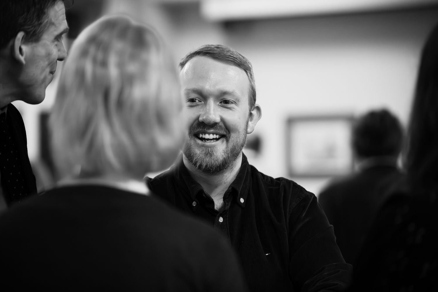 Bearded man smiling and laughing in black and white candid portrait photo.
