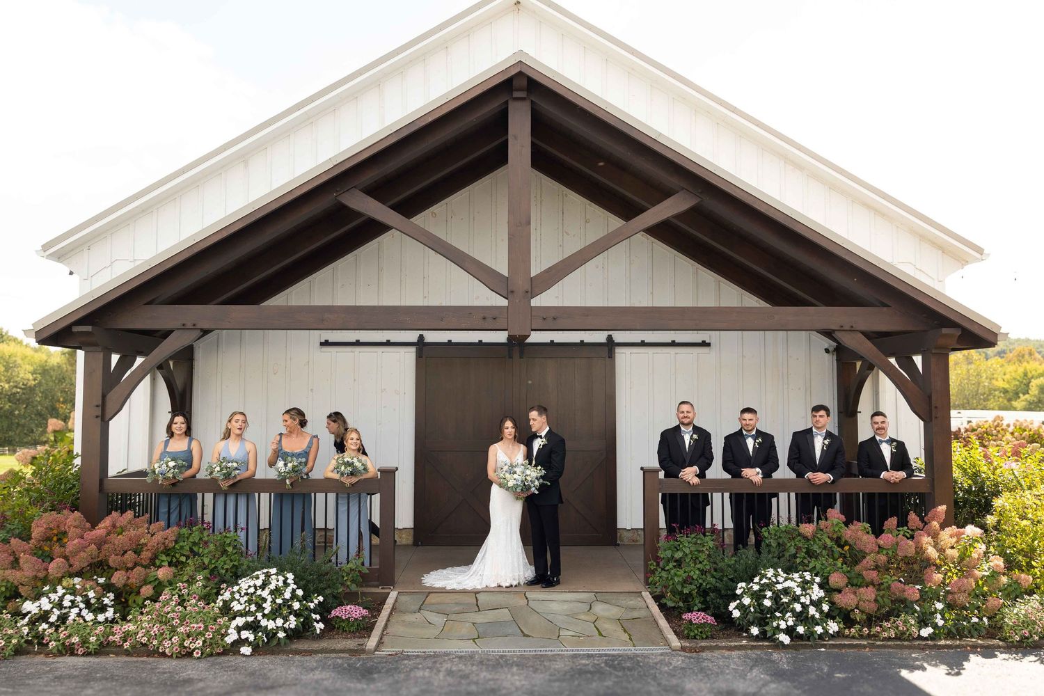 A wedding ceremony takes place under an elegant outdoor pavilion decorated with white flowers and greenery.