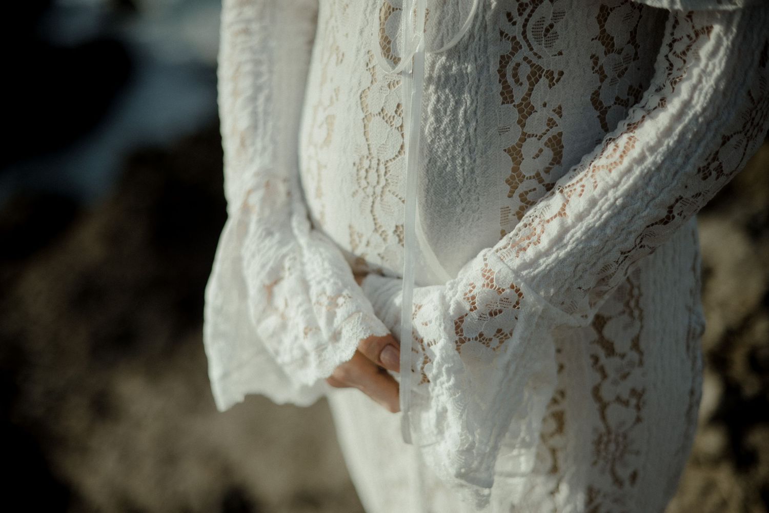 Close-up detail of delicate white lace fabric with intricate floral patterns and embroidered trim in natural lighting.