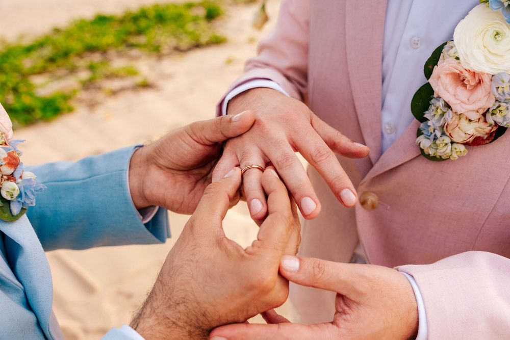 Hands wearing wedding rings are shown in a series of romantic close-up photos on a beach.