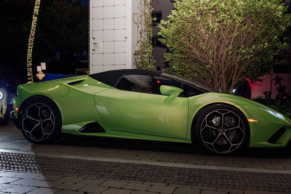 Lime green Lamborghini Huracan Spyder sports car parked outside at night.