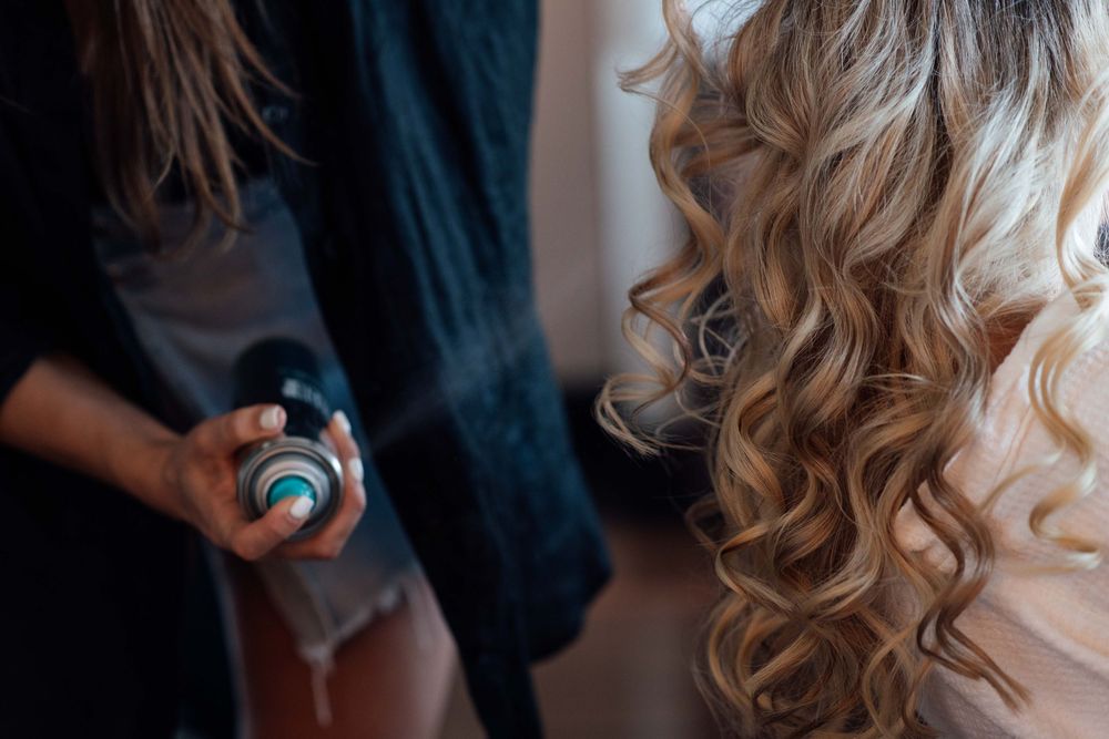 Hairstylist curling blonde womans hair in a modern luxury hotel suite kitchen.