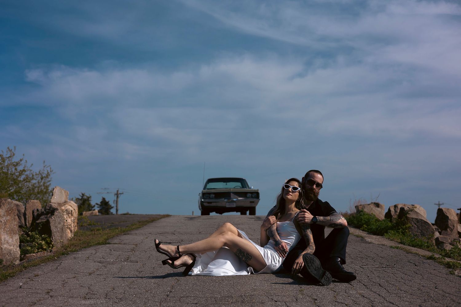 An engaged couple pose on a hilltop overlooking a scenic coastal New Bedford, MA, landscape on a summer day for their engagement photos.