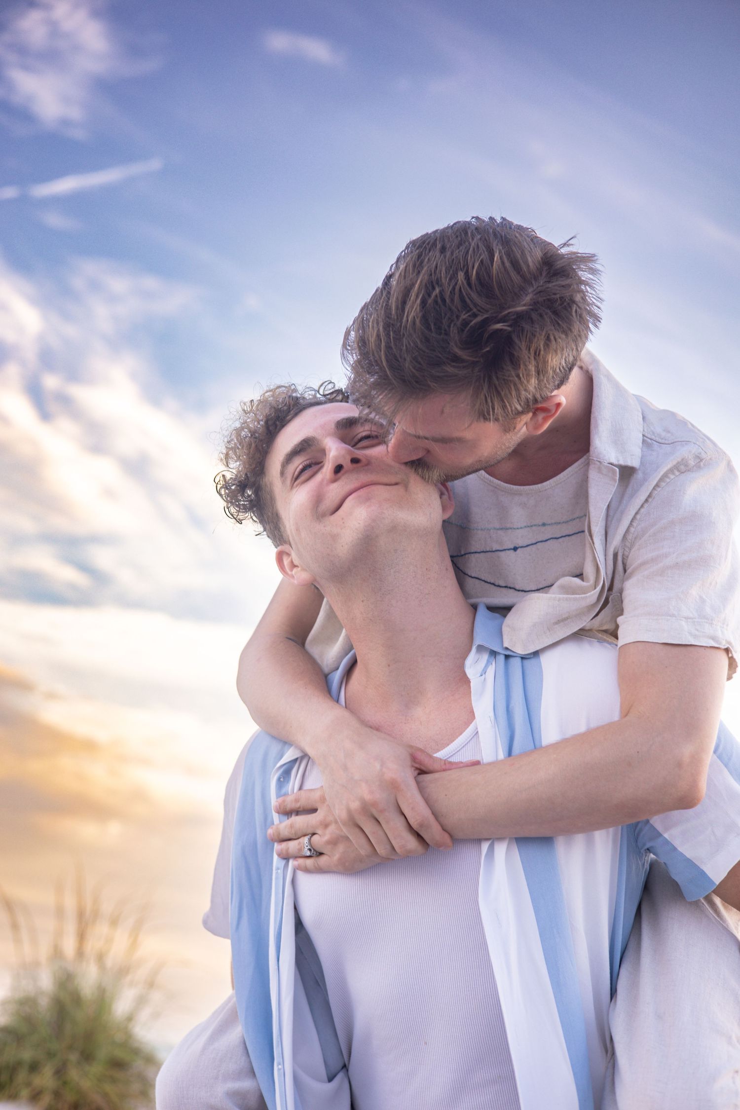 A mother holds her smiling young son on a beach at sunset, waves and pastel sky behind them. Lido Beach Florida