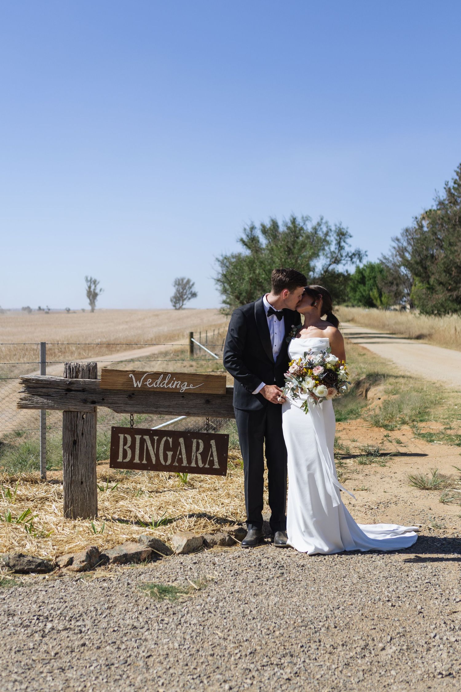 Bride and groom kissing near property entrance