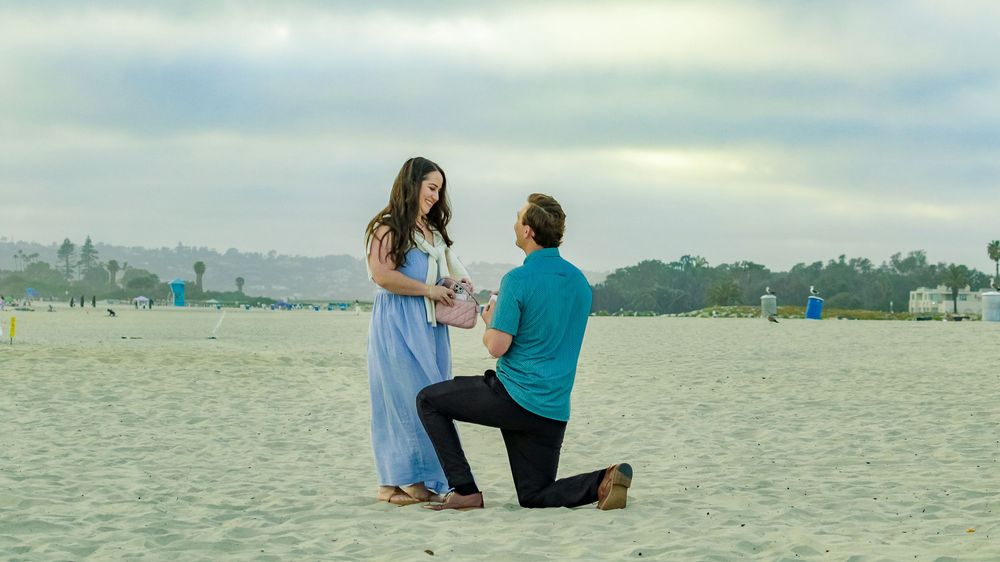Man down on one knee proposing on the beach at sunset captured by Zeus Holbrook Wedding Photographer San Diego