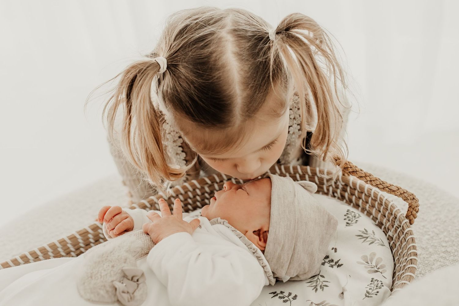 grote zus geeft baby een kus tijdens newborn fotoshoot gezin Soest