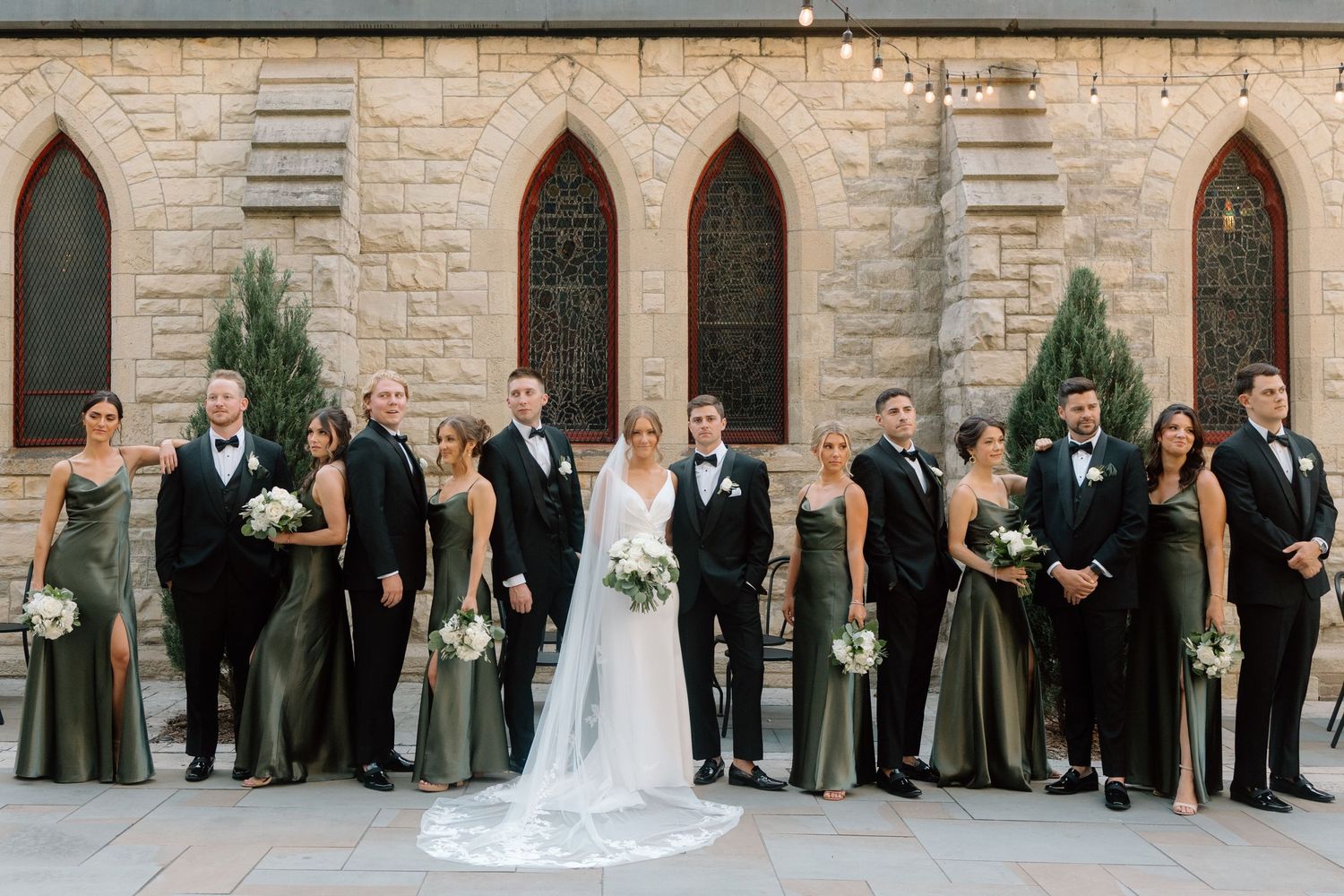 St James 1868 courtyard photos of a black tie wedding party posing outside with arched windows.