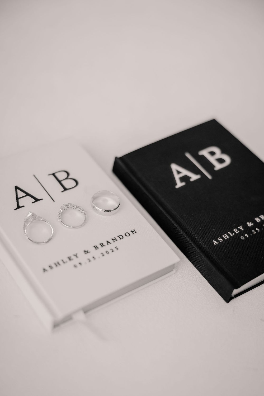 Wedding vow books with A|B monogram for Ashley and Brandon dated 09.23.2023 with rings on white cover.