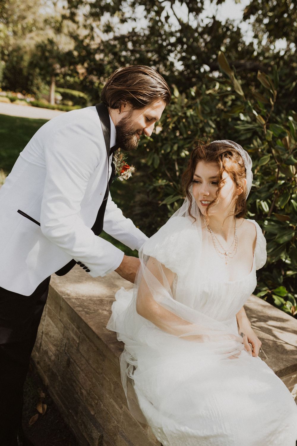 A romantic wedding photoshoot sequence showing a couple sitting together on a stone wall surrounded by greenery.