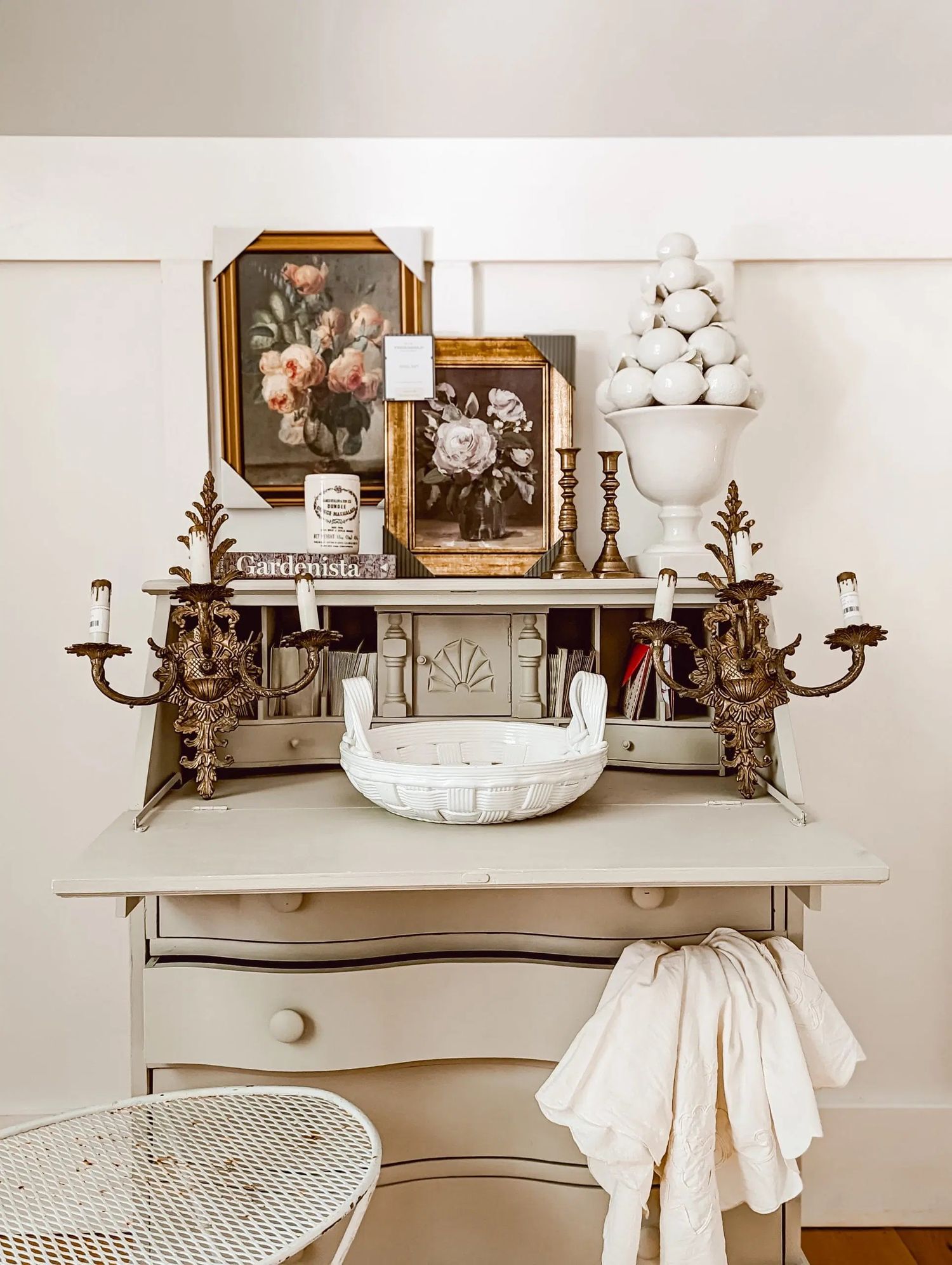 Vintage-style bathroom vanity decorated with antique brass sconces, framed artwork, and white cotton linens on display.