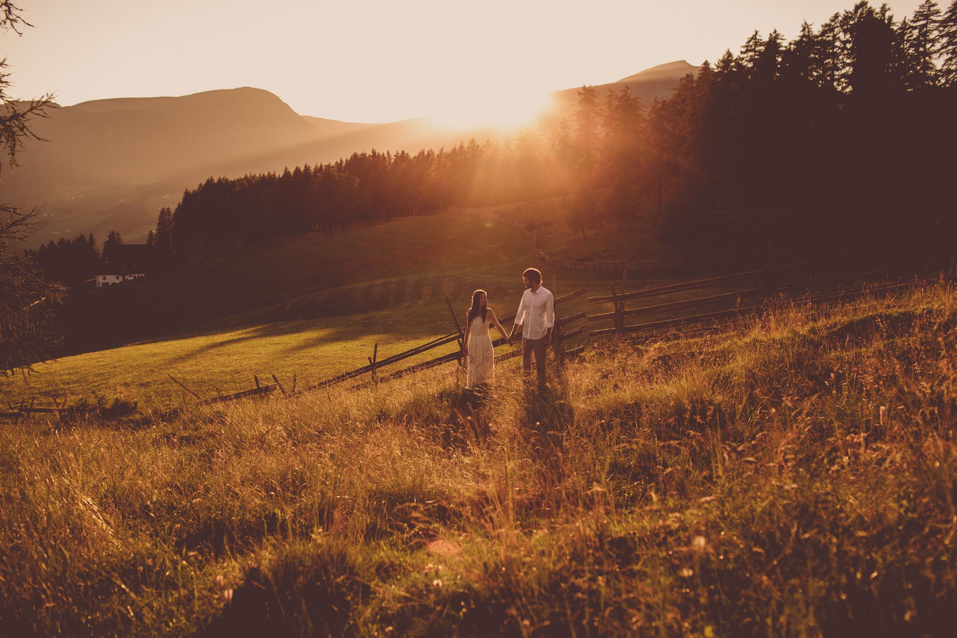 couple standing in sunset light at mountain meadow in the dolomites