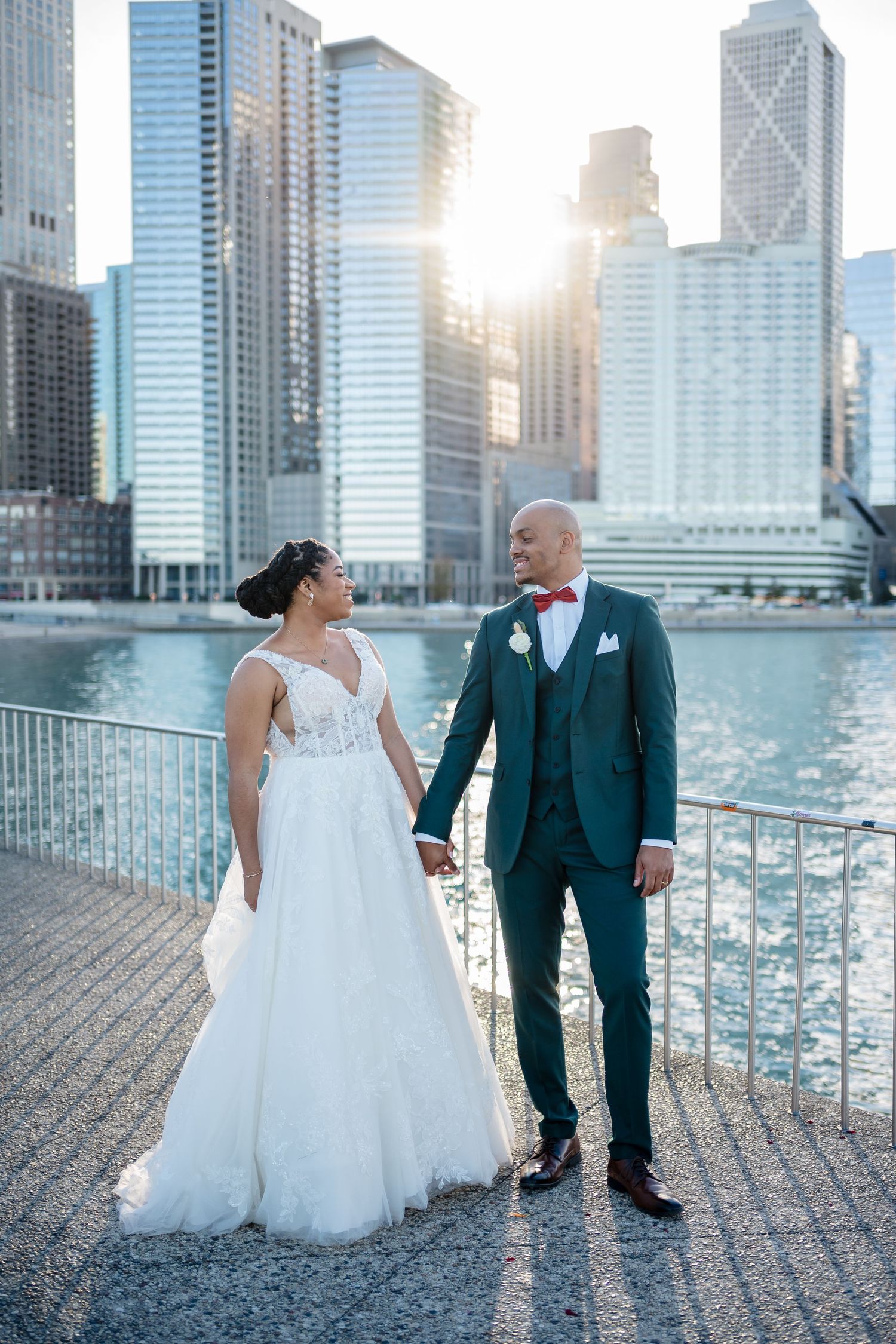 A couple shares a romantic moment along the Chicago riverwalk with stunning downtown skyscrapers in the background.