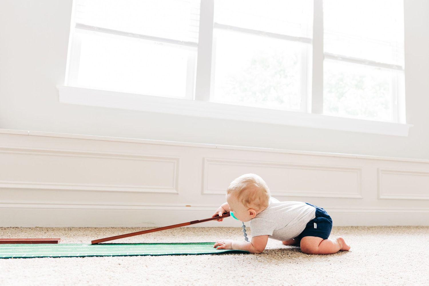 A photo showing a child playing with a putting set on a green mat at home.