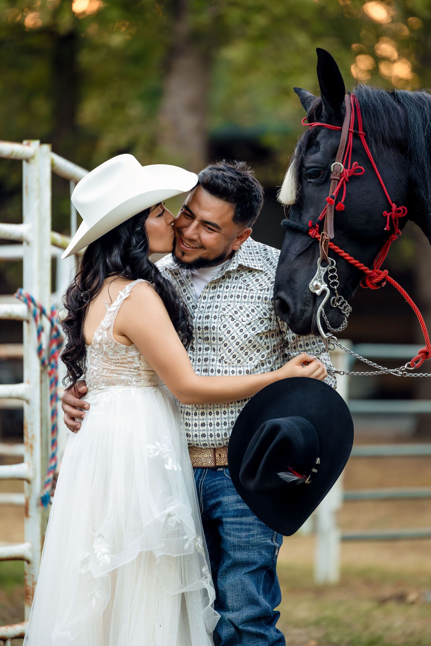 Romantic couple shares tender moments with a black horse during outdoor wedding photo session.