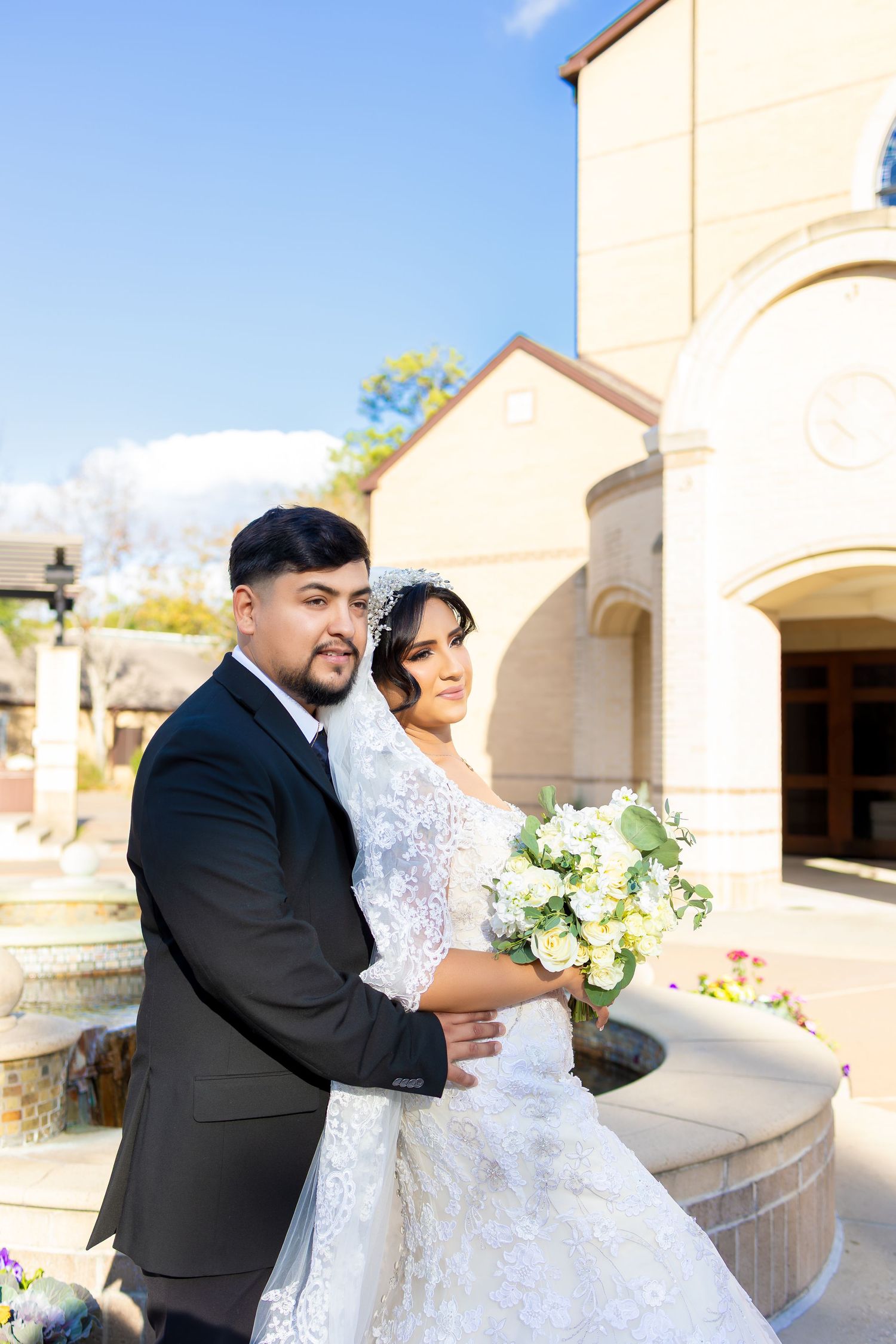 Newlywed couple posing for romantic portraits outside a Mediterranean-style church building.