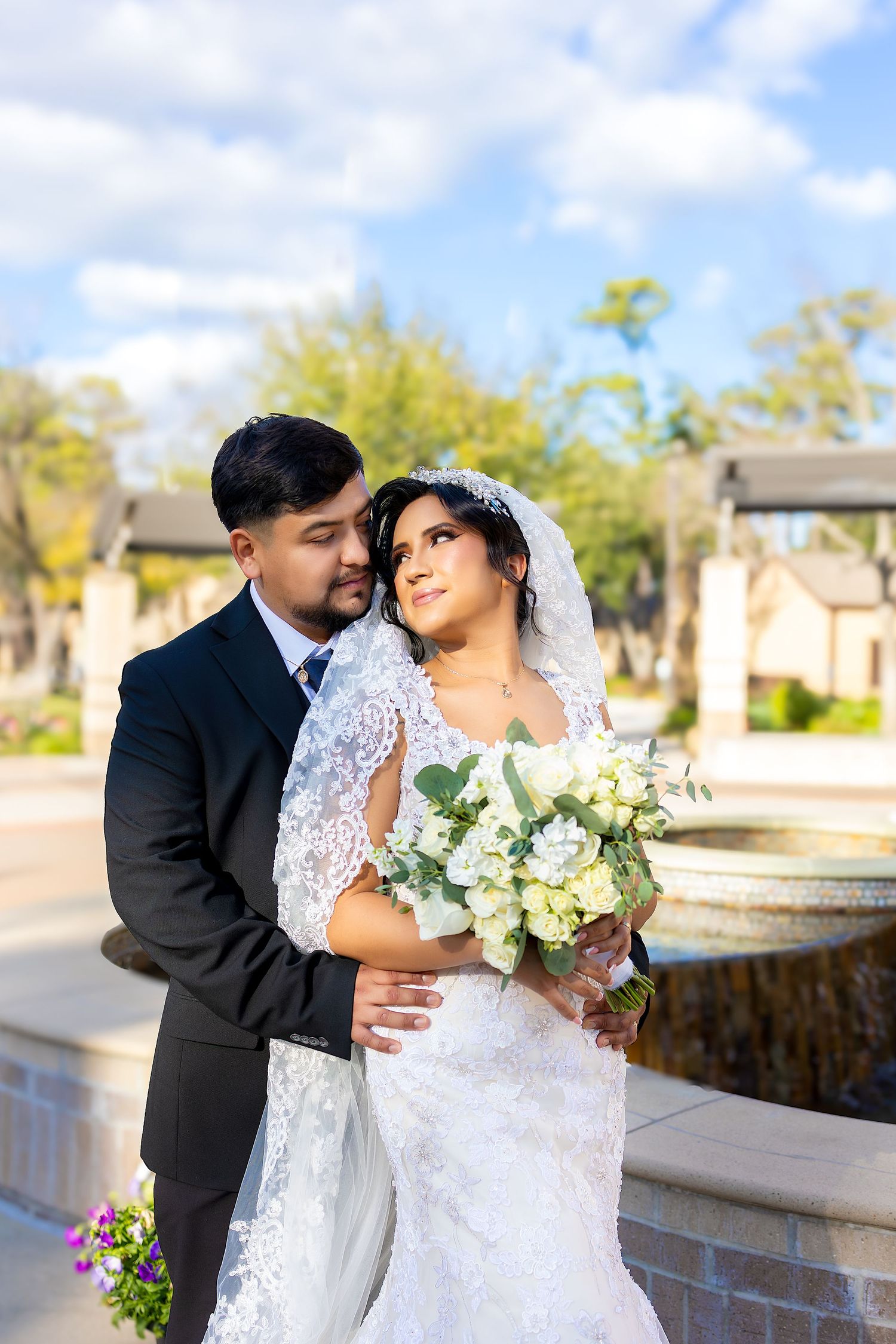 A couple shares romantic moments during their wedding photoshoot in an outdoor garden setting.
