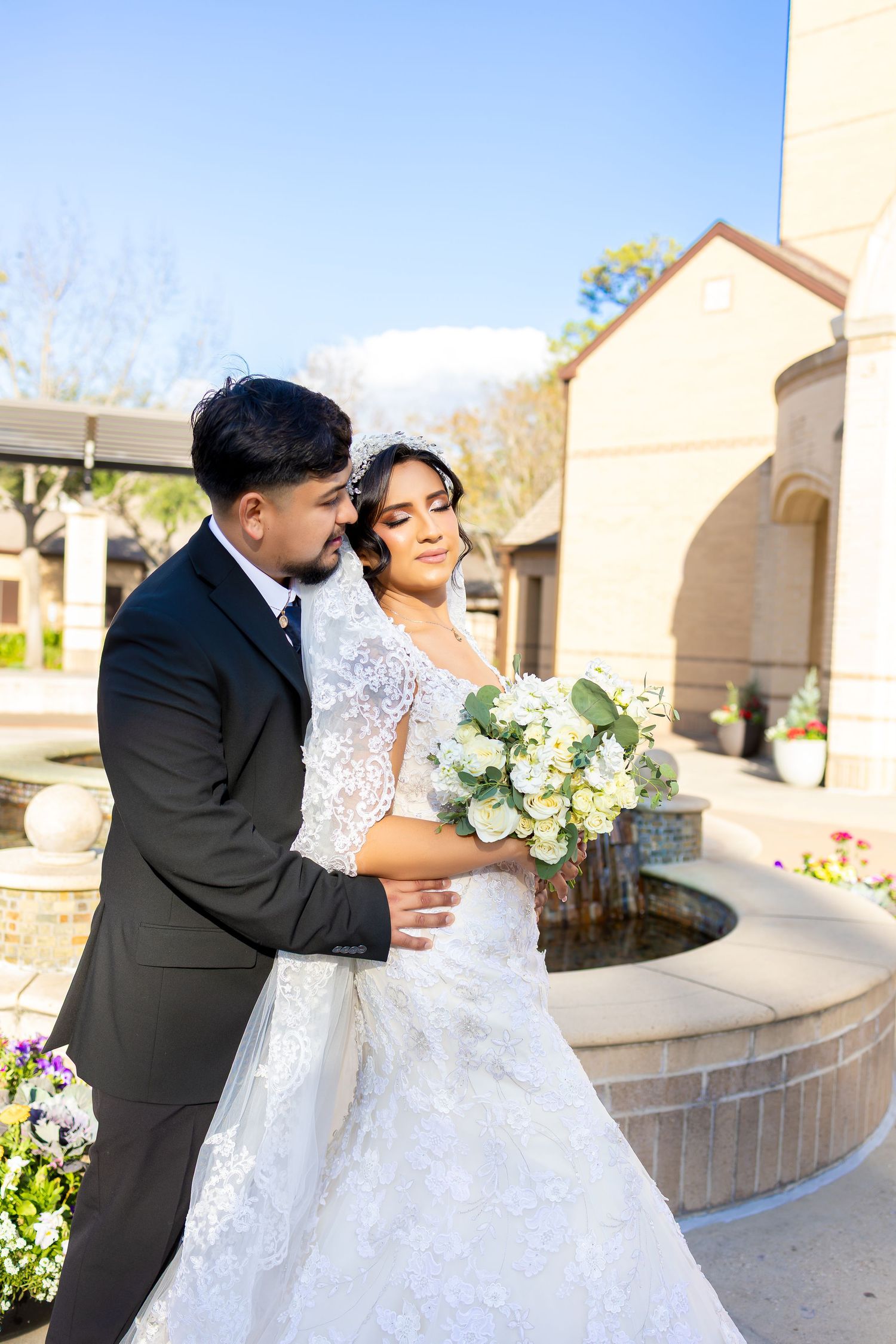 Outdoor wedding portraits showing a couple in formal attire near a stone fountain and church entrance.