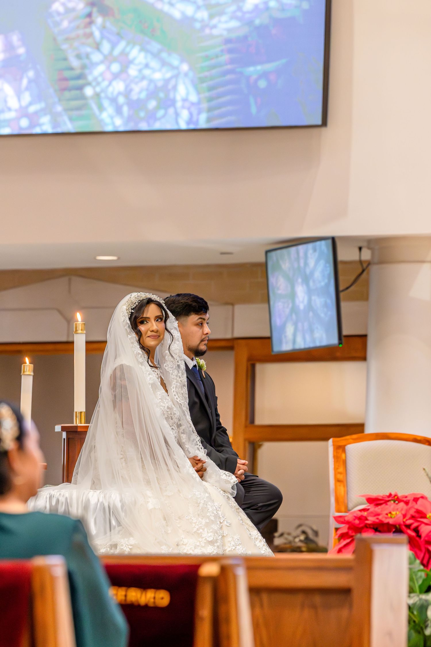 Wedding ceremony taking place inside a church with decorative lighting and wooden pews.