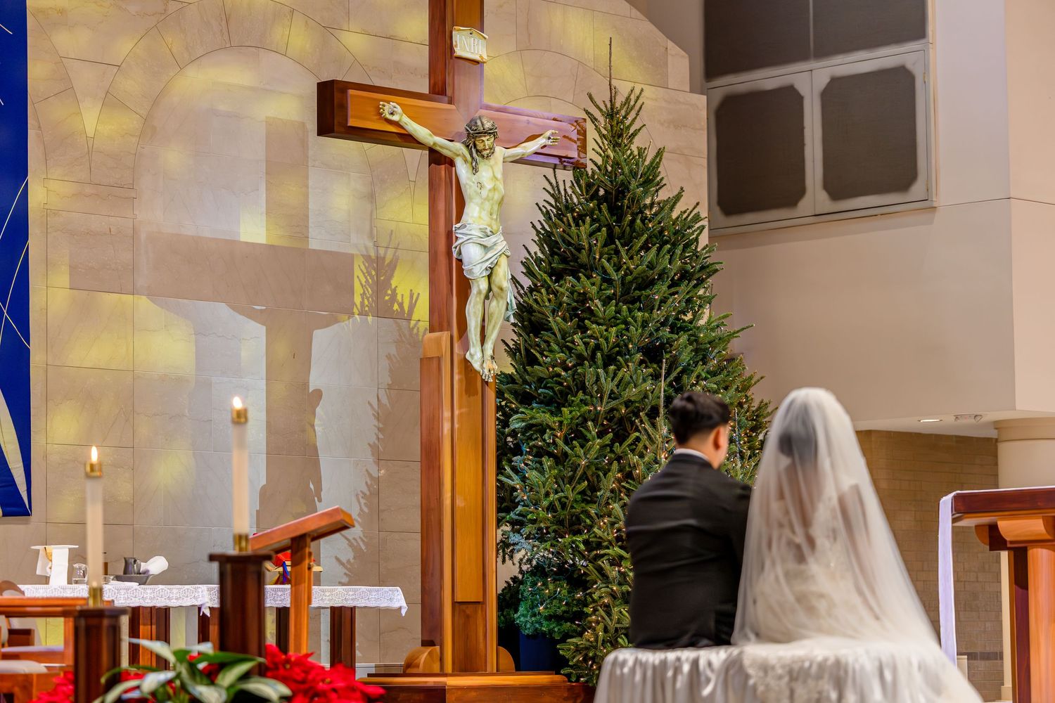 Church interior decorated for wedding ceremony with Christmas trees and white decor.