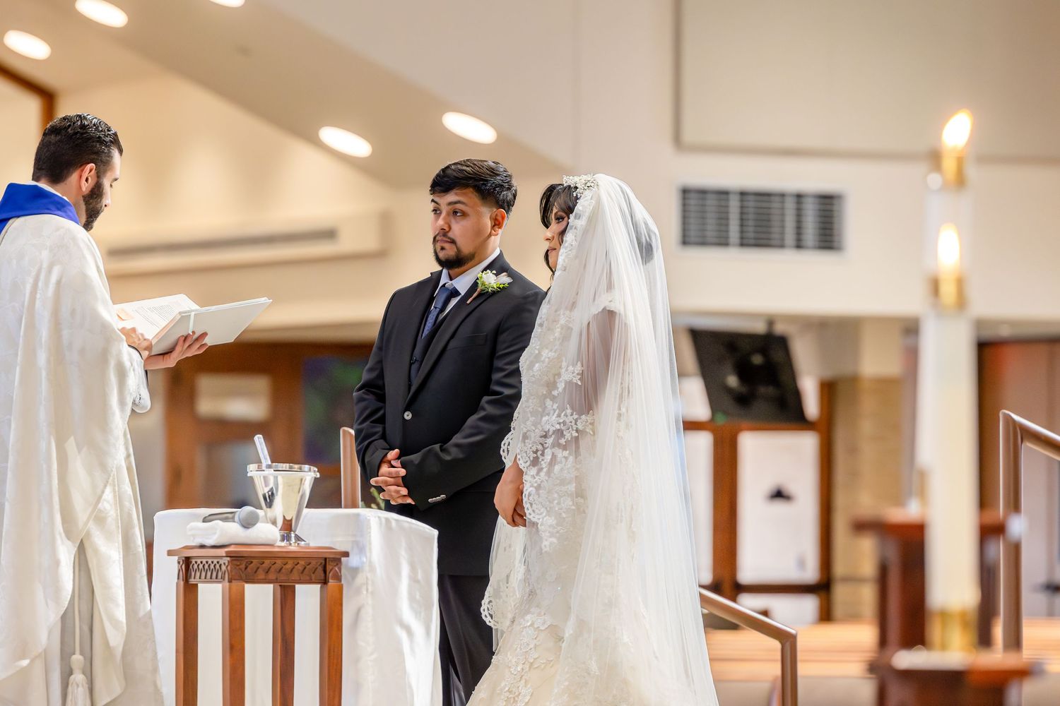 A wedding ceremony taking place in an elegant church interior with blue stained glass windows and decorative stars.